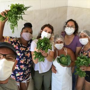 Cozinheiras da Cozinha Mãe etécnicos do Cepagro posam para foto segurança hortaliças nas mãos.