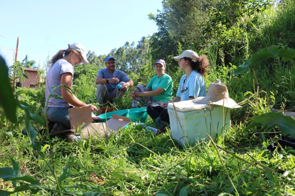Foto de grupo de pessoas reunidas em torno do canteiro de hortaliças.