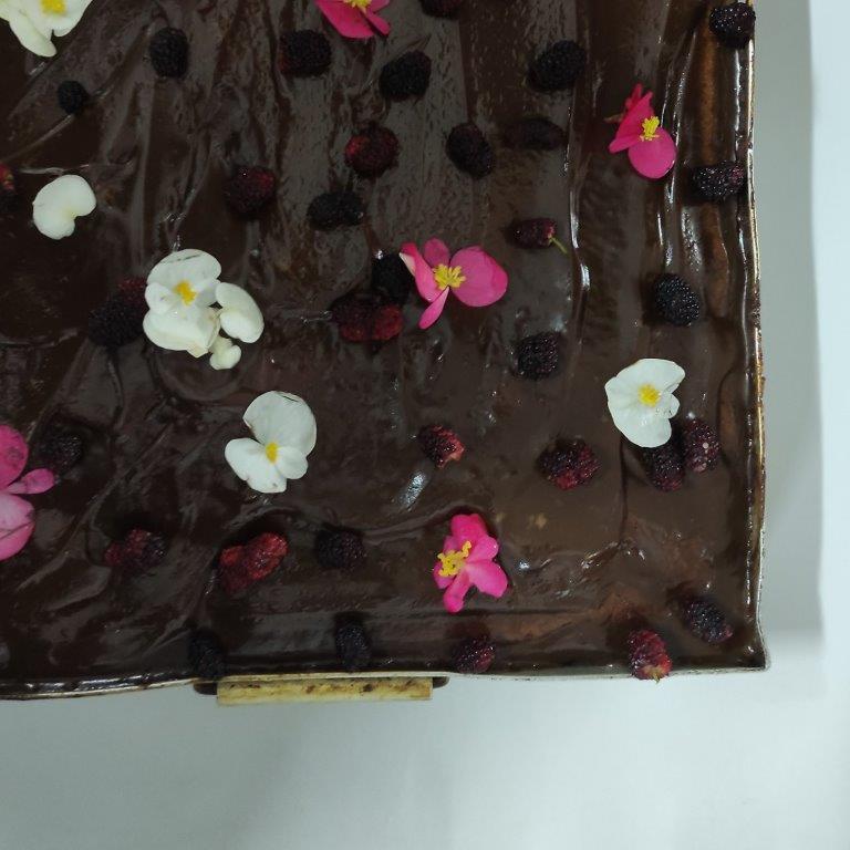 foto do bolo de menta com cobertura de chocolate decorado com flores e amoras vista de cima