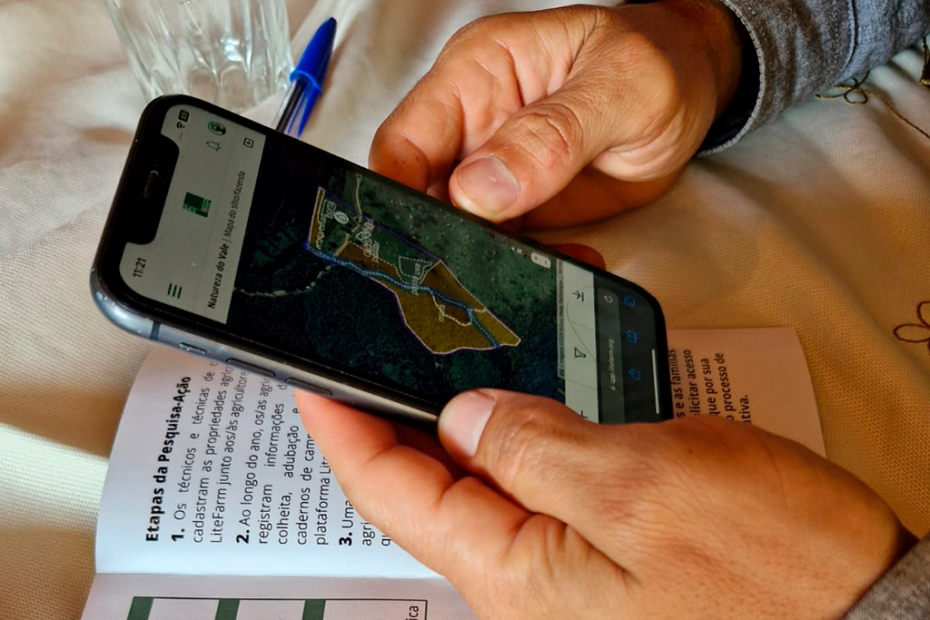 Mãos seguram um celular, onde pode se ver um mapa desenhado.