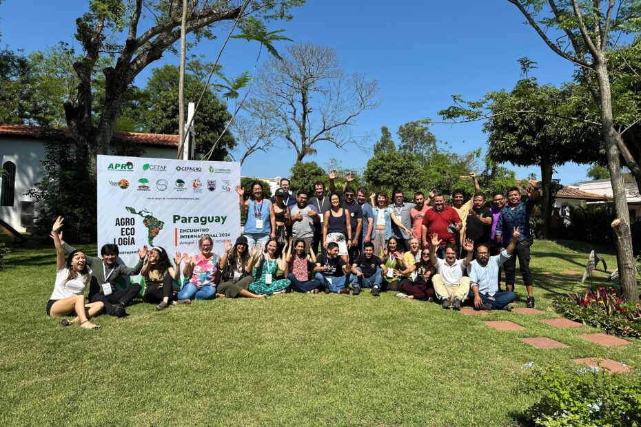Foto do Comitê Gestor do projeto "Agroecologia na América Latina: construindo caminhos" reunido ao lado de uma painel com o nome do projeto e as logos das organizações participantes.